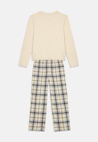 Cream-colored long-sleeve top paired with beige, black, and white plaid pants laid flat on a white background.