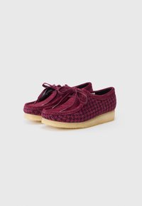 Pantofi din suede burgundy cu textură houndstooth, în formă rotundă, cu talpă plată și șireturi decorative în față. Design ușor.