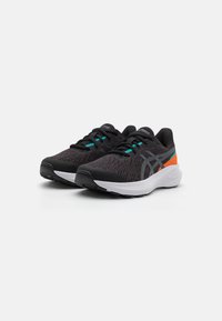 Baskets de sport noires avec une tige en mesh, des accents turquoise et une semelle blanche rembourrée avec une semelle extérieure en caoutchouc noir texturé.