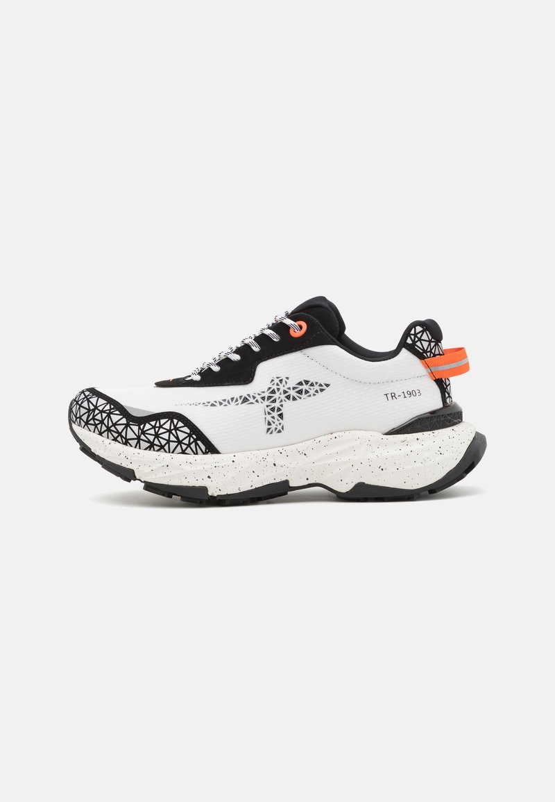 Zapatilla con una parte superior blanca y acentos negros, patrón geométrico en la puntera, detalles naranjas y una entresuela blanca moteada.