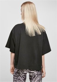 Čierne oversized tričko s krátkymi rukávmi, s okrúhlym výstrihom. V kombinácii s pruhovanými šedými a čiernymi nohavicami s motívom zebry.