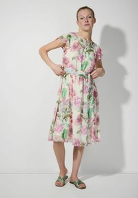 Blumenkleid aus leichtem, transparentem Stoff mit rosa und grünen Blumenmustern. Mit kurzen Ärmeln und einem taillierten Gürtel versehen.