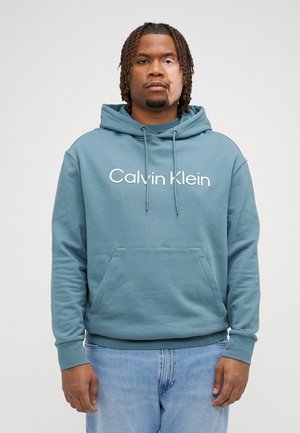 Felpa blu realizzata in tessuto morbido con tasca frontale, cappuccio con cordino e il logo "Calvin Klein" in bianco ben visibile.