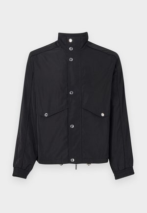 Schwarze Jacke aus glänzendem Stoff, mit Stehkragen, zwei Fronttaschen, Knopfverschluss und elastischen Bündchen. Silberne Hardware-Akzente.