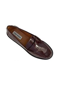 Mocassino in pelle verniciata bordeaux con cuciture a mocassino, design slip-on e suola in gomma nera; presenta un'etichetta che recita "Steve Madden."