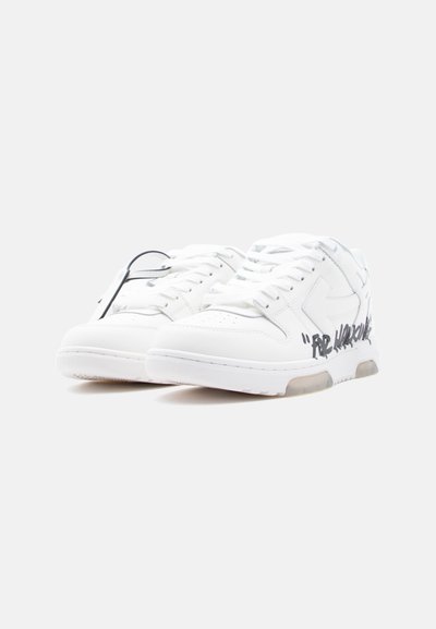 Ζευγάρι λευκά χαμηλά πάνινα παπούτσια με μαύρο κείμενο σε στιλ γκράφιτι στην εξωτερική πλευρά και λευκά κορδόνια σε λευκό φόντο.