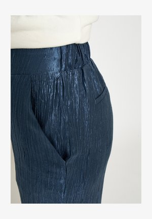 Donkerblauwe broek met gerimpelde textuur, elastische tailleband en zijzakken. De stof heeft een subtiele glans en een gestructureerd ontwerp.