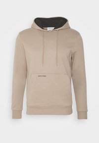 Sudadera beige con capucha negra forrada, cordones y un bolsillo frontal que presenta un pequeño logo impreso. Tejido suave, puños y dobladillo acanalados.