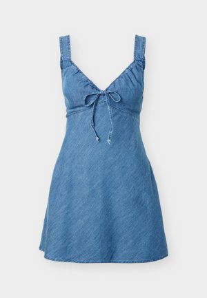Bezrekawowa mini sukienka z denimu z szerokimi ramiączkami i kokardą z przodu przy dekolcie w kształcie litery V, lekko rozszerzająca się ku dołowi.