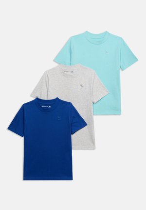 Tre magliette a maniche corte con scollo a girocollo nei colori blu, grigio e turchese chiaro, ciascuna con un piccolo logo di alce ricamato sul petto.