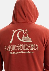 Sweatshirt à capuche rouge avec un graphique blanc de vagues et du texte. Tissu doux au coupe décontractée, conçu pour le confort et les activités en extérieur.