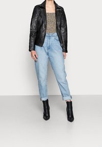 Svart bikerjacka i läder med ribbad detalj, blommig topp, ljusblå högmidjade jeans och svarta ankelstövlar med spetsiga tår.