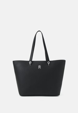Bolso tote de cuero negro con una superficie texturizada, acentos de hardware plateado y un logo en la parte frontal. Cuenta con dos asas largas.