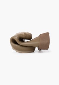 Herramienta de silicona beige flexible con superficie texturizada, una funda de tela suave y una forma contorneada para un uso ergonómico, con estrías pronunciadas.