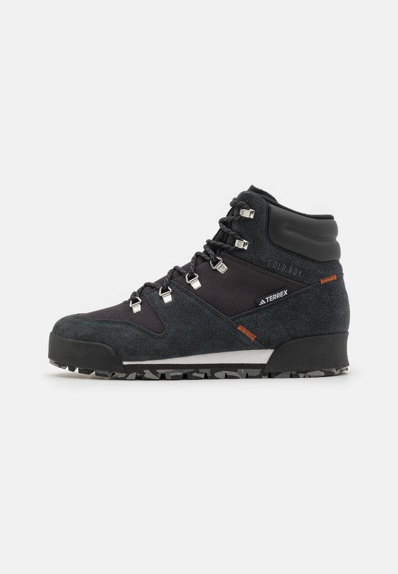 Botas de caminhada de meio cano em preto e cinza, feitas de materiais de camurça e sintéticos, com ferragens prateadas e sola de borracha resistente com um padrão texturizado.