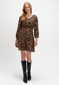 Sukienka w panterkę z długimi rękawami i dekoltem w kształcie litery V, ściągnięta w talii. W zestawie z wysokimi czarnymi botkami. Gładka faktura.