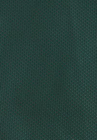 Dark green mesh fabric with a diamond pattern, featuring a textured surface and visible open spaces for breathability.