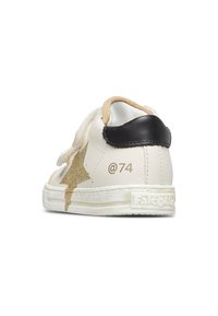 Sneaker bianco in pelle con accento di stelle glitter oro, tassello sul tallone nero e strap in velcro. Presenta suede testurizzato e branding "Falcotto".