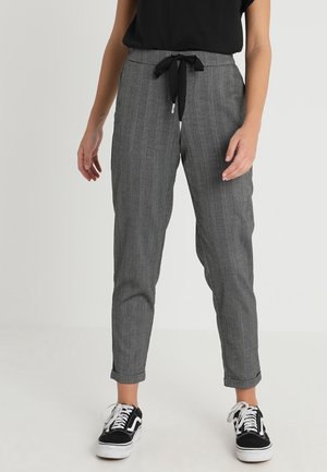 Pantalons rayés gris avec une coupe décontractée, dotés d'une taille à nouer et d'ourlets roulés. Associés à des baskets noires. Texture de tissu lisse.