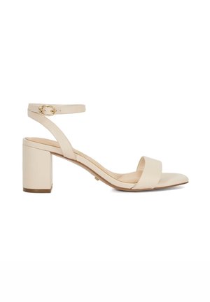 Sandale à semelle bloc beige avec une large bride à orteils et une fine bride à la cheville. Dotée d'une boucle dorée et d'une texture en cuir lisse.