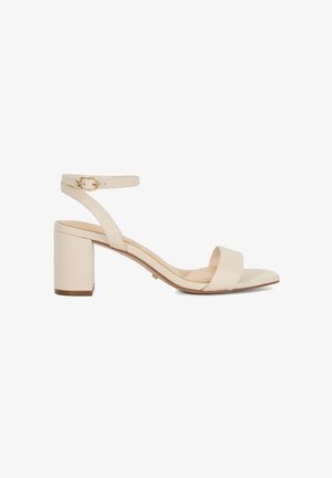 Beige block-heeled sandal with a wide toe strap and a slender ankle strap. Features a gold buckle and smooth leather texture.