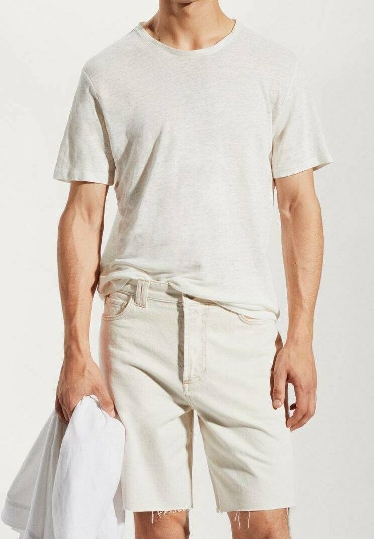 T-shirt beige clair à manches courtes et col rond, associé à un short beige clair assorti avec un ourlet effiloché.