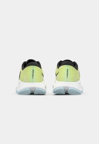 Lichtgroene sport schoenen met zwarte accenten, voorzien van een gestructureerde mesh bovenkant, een gedempte zool en blauwe rubberen details aan de onderkant.