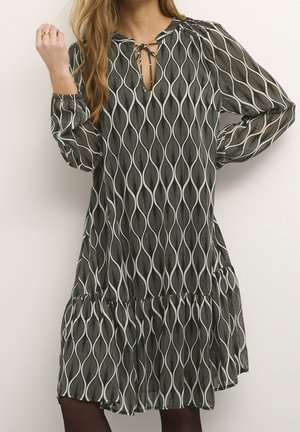 Robe shift à manches longues en noir et blanc avec un motif de vagues, dotée d'un col smocké, d'un détail en trou de serrure et d'un ourlet à volants superposés.
