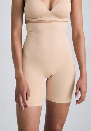 Shorts taille haute nude fabriqués dans un tissu lisse et extensible avec une coupe ajustée et une ceinture sans couture pour plus de confort et de soutien.