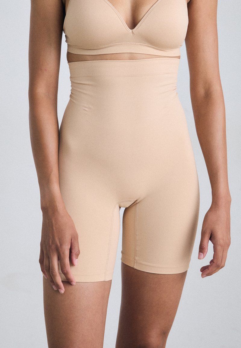 Nude high-waisted shorts gemaakt van een gladde, rekbare stof met een aansluitend ontwerp en een naadloze tailleband voor comfort en steun.