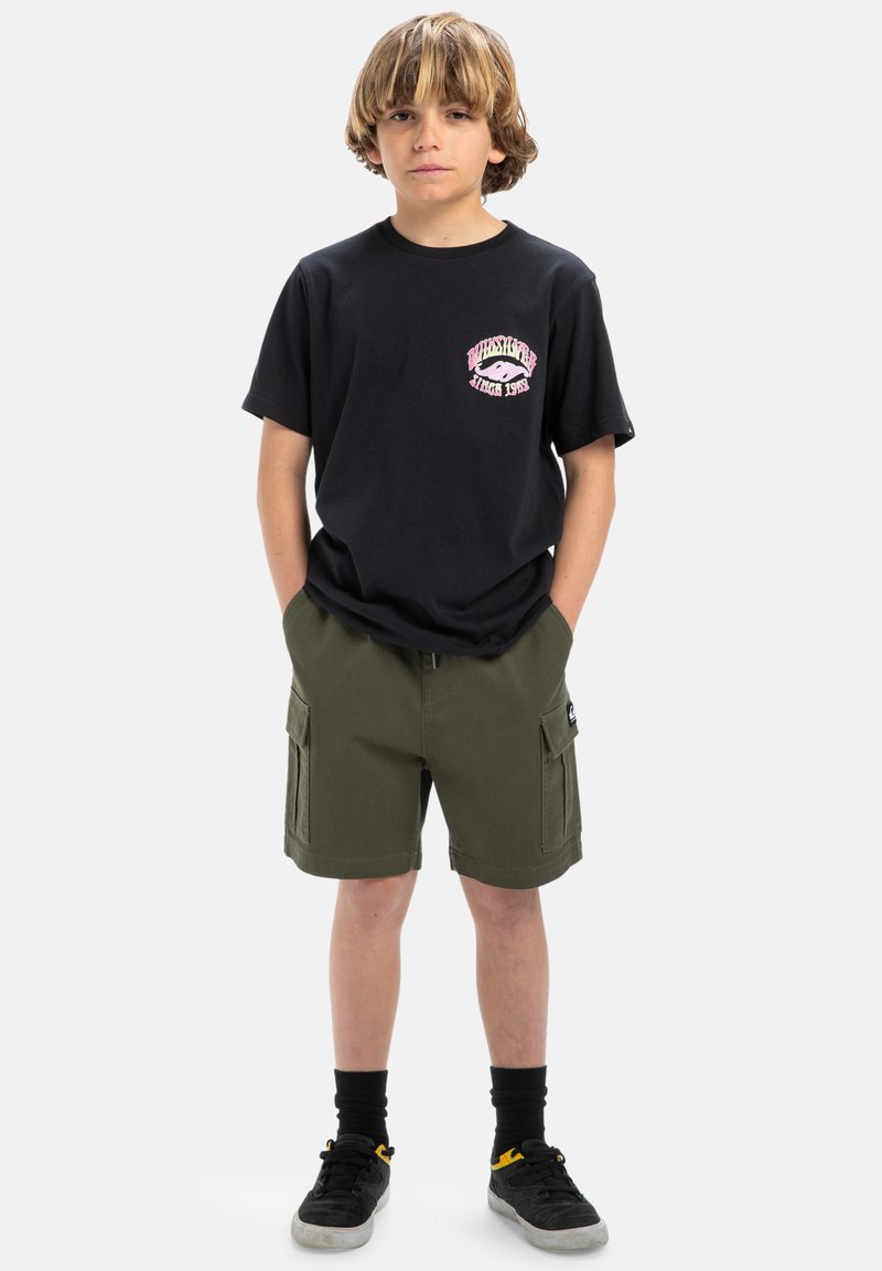 Svart bomullströja med rosa grafisk tryck på bröstet, kombinerad med olivgröna cargoshorts. Svarta strumpor och skor fulländar looken.