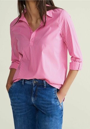 Rosa gestreiftes Hemd mit Kragen, Dreiviertelärmeln und lockerer Passform, kombiniert mit blauen Jeans aus Denim mit leichtem Verblassen.