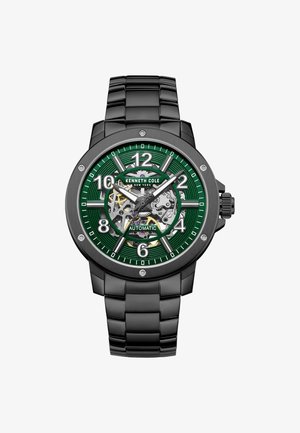 Zwart metalen horloge met een groene gestructureerde wijzerplaat, grote cijfers en een transparante achterkant die de tandwielen toont. Voorzien van een roestvrijstalen band.