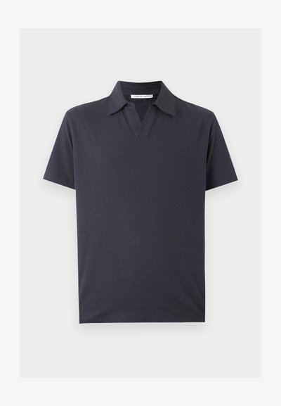 Σκούρο μπλε μπλουζάκι πόλο με κοντά μανίκια, ανοιχτό γιακά και απαλό βαμβακερό ύφασμα, παρουσιάζεται σε ανοιχτό φόντο.