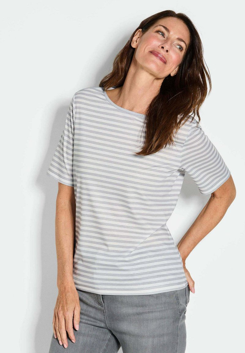 Gestreepte kortemouwen top in lichtgrijs en wit; heeft een ronde halslijn en een ontspannen pasvorm. Zachte stof. Gecombineerd met grijze broek.
