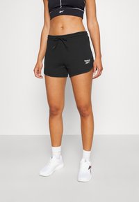Pantaloncini atletici neri con vita regolabile con coulisse e logo Reebok, realizzati in materiale morbido, con design aderente e texture liscia.