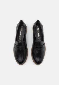 Scarpe in pelle nera con punta rotonda, dettagli di cucitura sottili, suola piatta e un leggero tacco. Nome del marchio "Tamaris" visibile all'interno. Taglia 37.