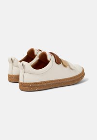 Chaussures en cuir blanches avec des accents marron et or, des sangles Velcro et une semelle en caoutchouc texturée présentant un design tacheté.