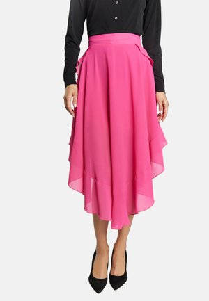 Donna che indossa una gonna midi fluida asimmetrica di colore rosa brillante abbinata a un top nero a maniche lunghe con bottoni e tacchi neri a punta.