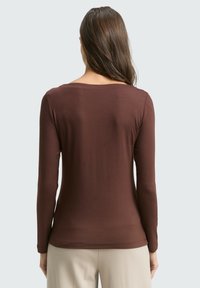 Braunes Langarmshirt aus weichem Stoff, mit einem dezenten Rundhalsausschnitt und figurbetonter Passform, von hinten betrachtet.