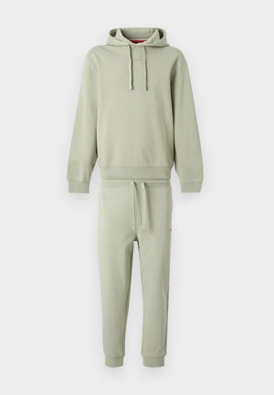 Svetlozelená mikina s kapucňou a šnúrkami, v kombinácii s nohavicami do pásku s manžetami na členkoch.