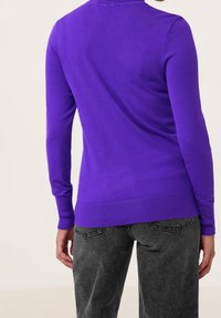 Pull en tricot violet à manches longues et encolure ronde, associé à un pantalon gris foncé. Les poignets et l'ourlet côtelés présentent une texture lisse.