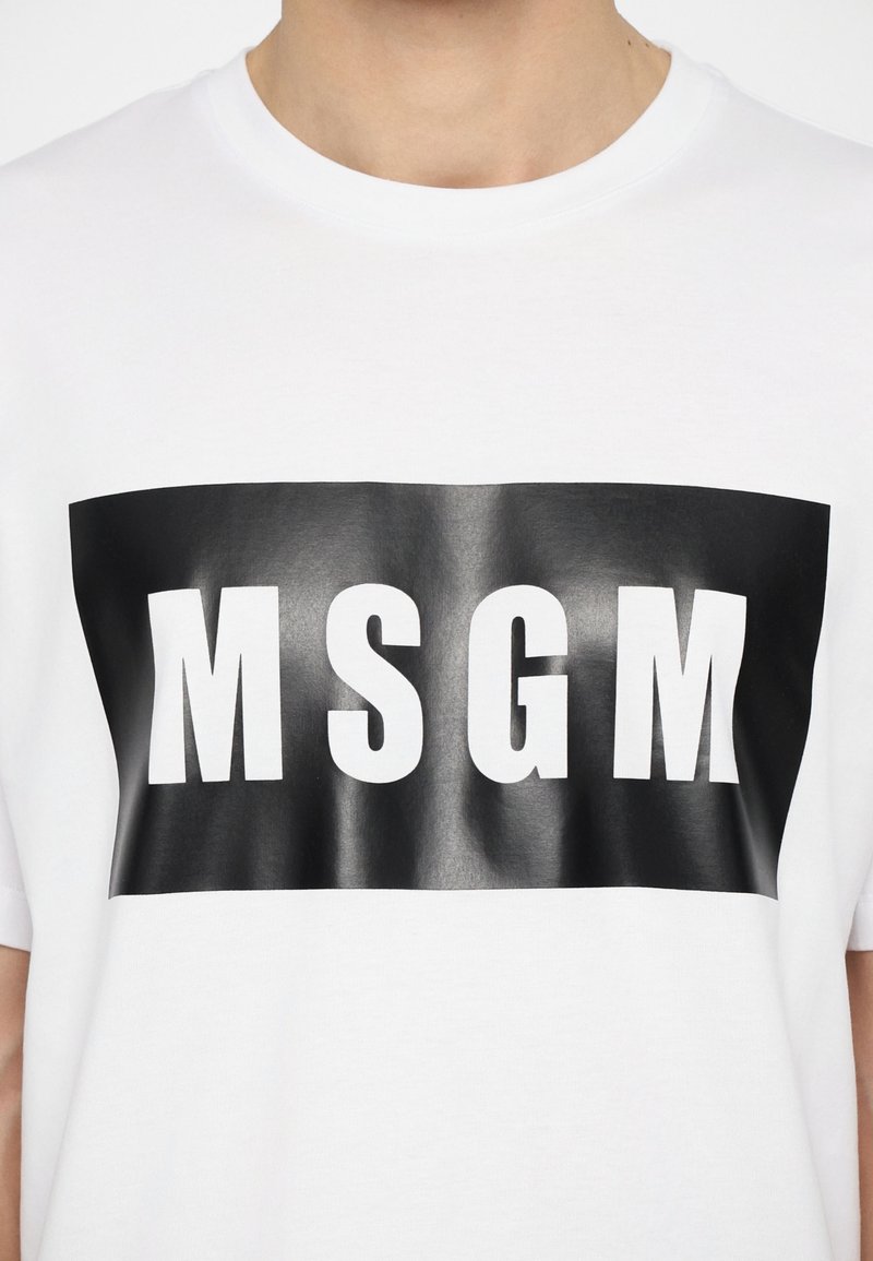 Hvid bomulds t-shirt med et sort rektangulært grafik, der har fede hvide bogstaver "MSGM" i midten. Blød tekstur, rund halsudskæring.