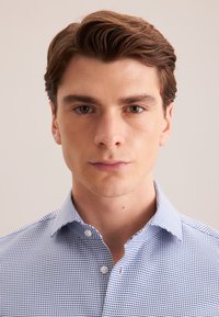 Camicia button-up con un motivo geometrico blu e bianco, design con colletto e maniche corte. Tessuto liscio con una vestibilità strutturata.