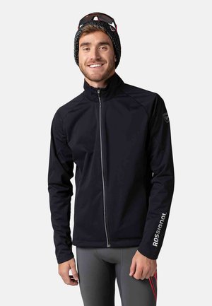 Schwarze, enganliegende Jacke mit hohem Kragen und durchgehendem Reißverschluss, mit langen Ärmeln und Rossignol-Logo auf dem linken Arm. Glatte Textur, sportliches Design.