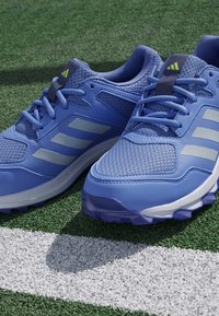 Modré atletické tenisky z jemného a syntetického materiálu, s tromi bielymi pruhmi, textúrovaným povrchom a gumovou podrážkou.