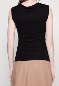 Top nero senza maniche con un design aderente, caratterizzato da una texture arricciata sul retro. Il materiale appare morbido e leggermente elasticizzato.