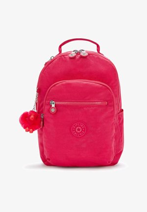 Różowy plecak o miękkiej fakturze, z zamkami błyskawicznymi w kieszeniach i futrzanym breloczkiem w kształcie małpki. Posiada okrągłe logo i dopasowane uchwyty zamków.