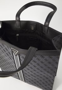 Sac fourre-tout noir avec motif logo, poignées élégantes et poche zippée. Présente un détail de rayure grise et des accents en cuir lisse à l'intérieur.