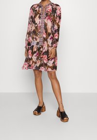 Kukkakuvioinen mekko vaaleanpunaisen ja ruskean sävyissä, pitkät hihat, pyöreä pääntie ja monimutkaiset kirjailtavat yksityiskohdat edessä.